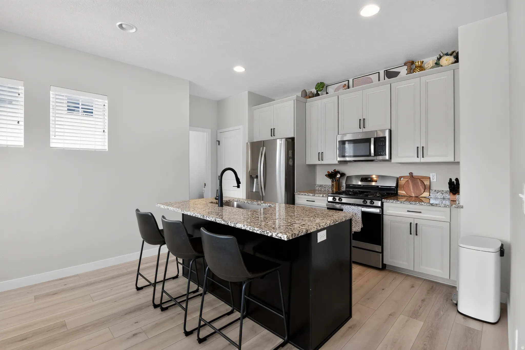 Modern kitchen featuring light wood-finish flooring and a central island with granite countertops