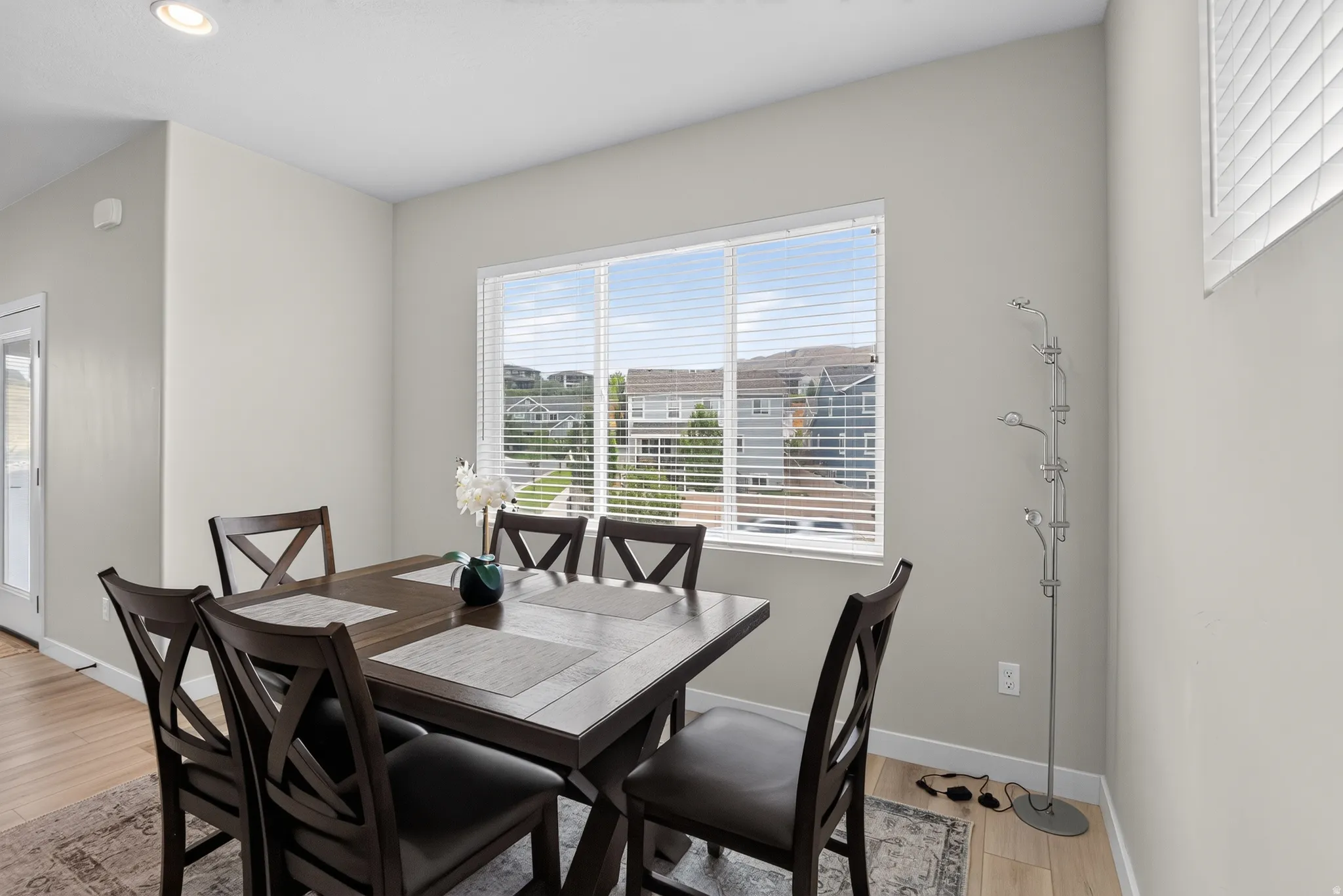 Dining area featuring a large window with horizontal blinds, light wood-finish flooring, and recessed ceiling lighting
