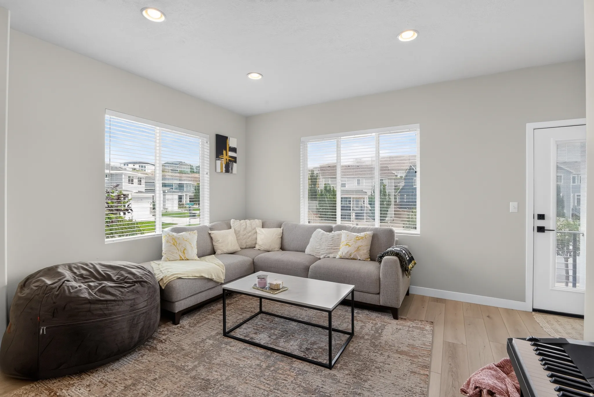 Bright living space featuring expansive windows, recessed lighting, light wood-finish flooring, and a white paneled door with a frosted glass insert