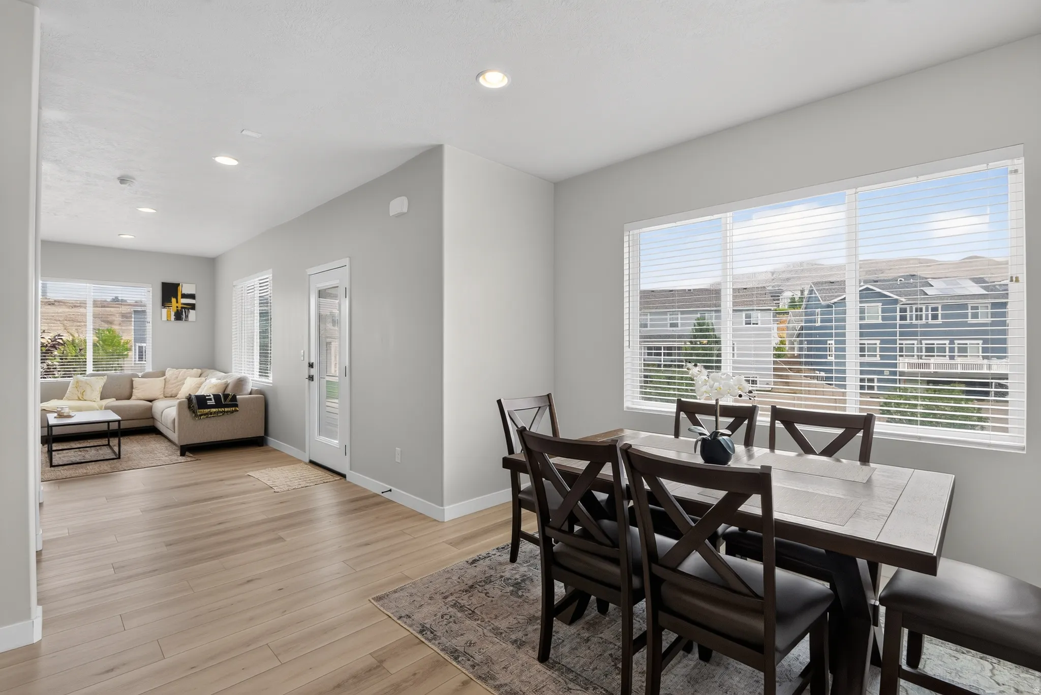 Open-concept living and dining areas featuring light wood-finish flooring, recessed lighting, and ample natural light from multiple windows