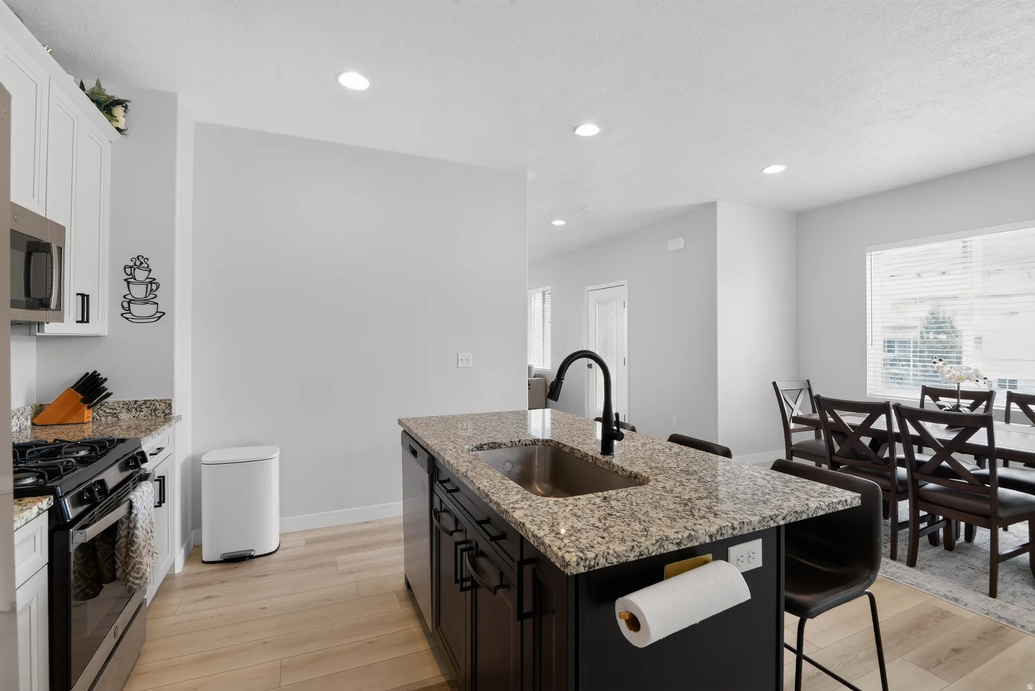 Kitchen island featuring a granite countertop, undermount sink, and matte black faucet