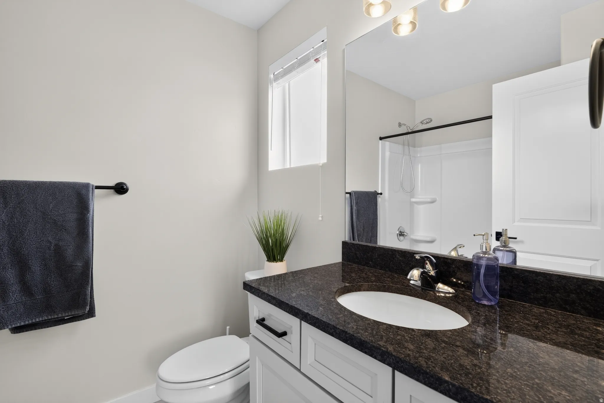 Bathroom featuring a vanity with a dark speckled countertop, undermount sink, and chrome faucet