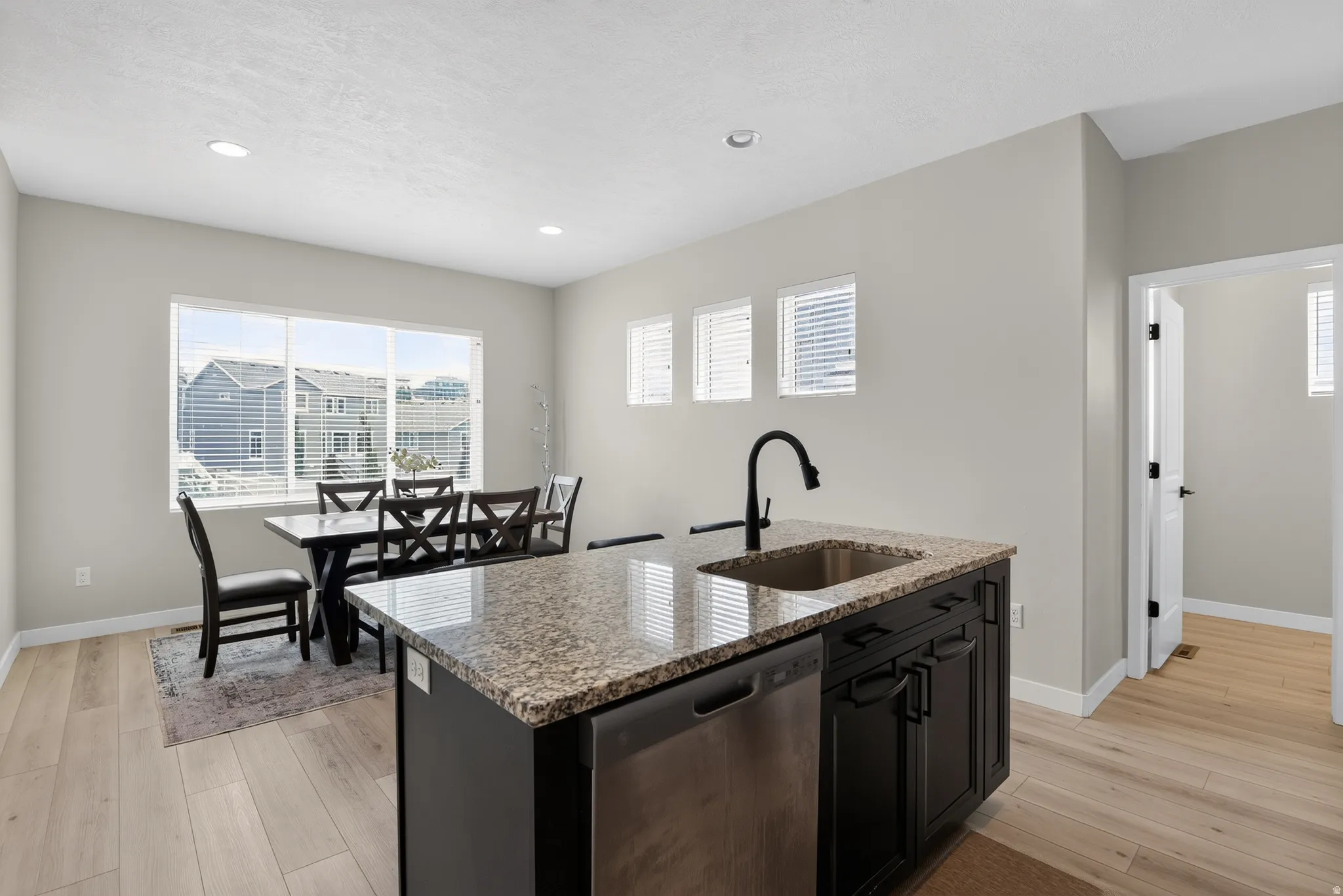 Kitchen island featuring a granite countertop, undermount sink, and matte black faucet
