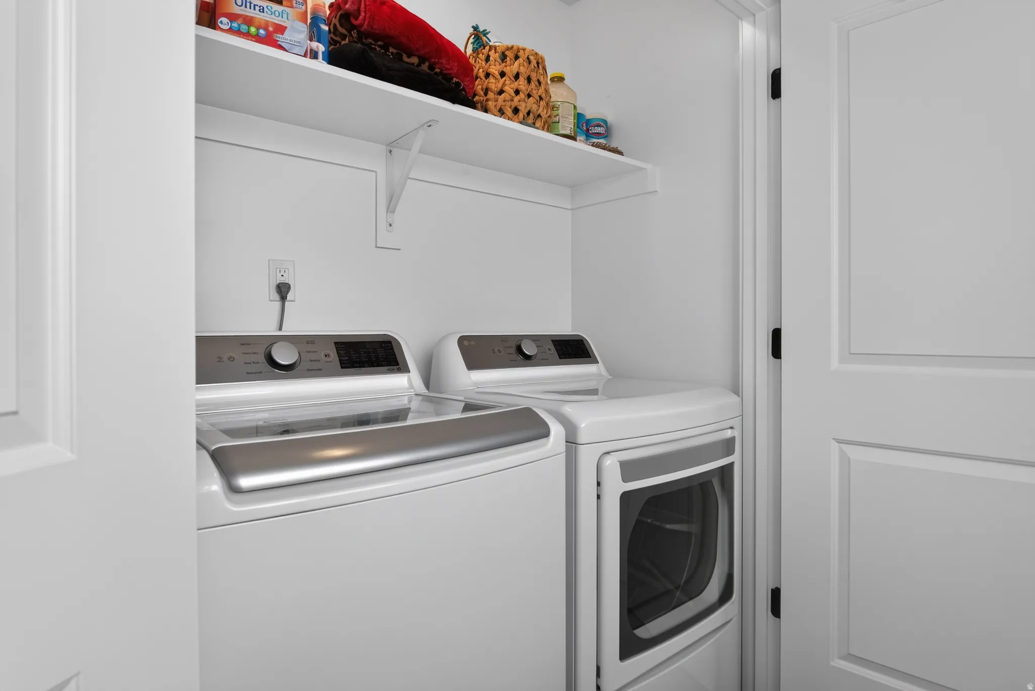 Laundry area featuring a top-load washing machine, front-load dryer, and wall-mounted shelving