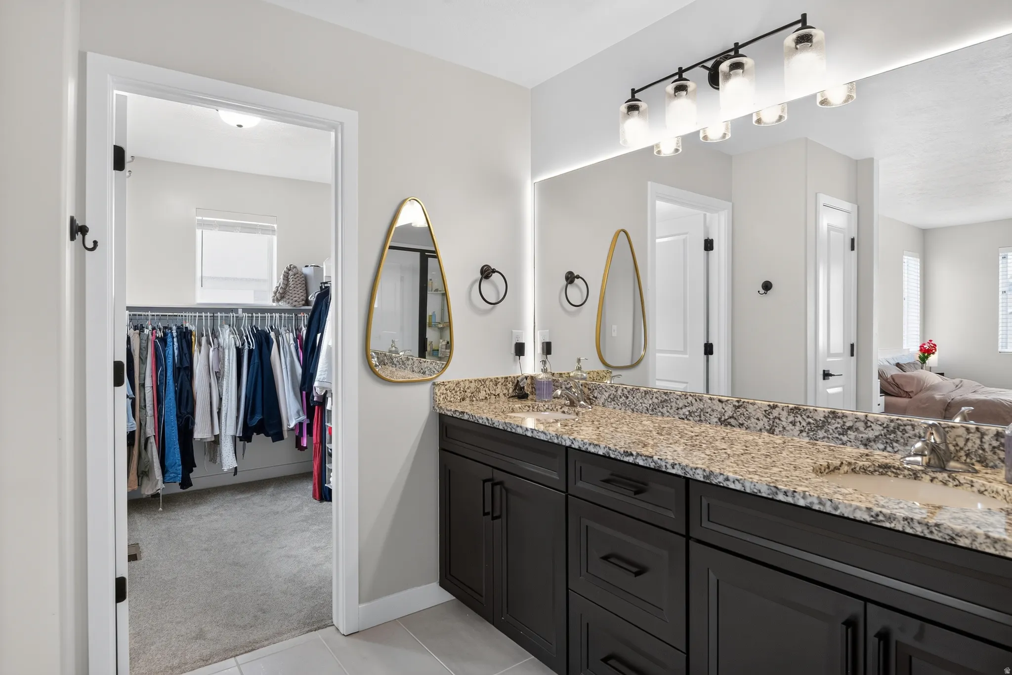Bathroom vanity with dual undermount sinks, granite countertop, and dark wood cabinetry