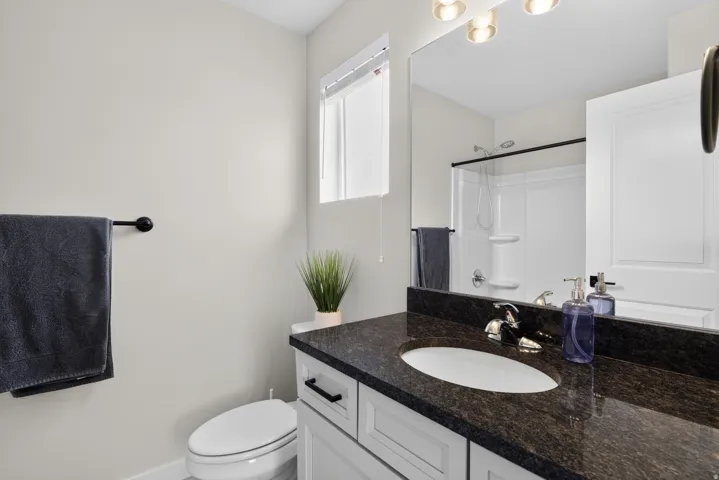 Bathroom featuring a vanity with a dark speckled countertop, undermount sink, and chrome faucet