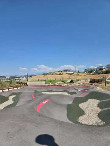 Outdoor pump track featuring asphalt and gravel surfaces with crimson accents