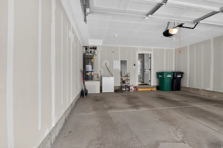 Spacious garage featuring a concrete floor, painted drywall, overhead garage door with opener, and utility access