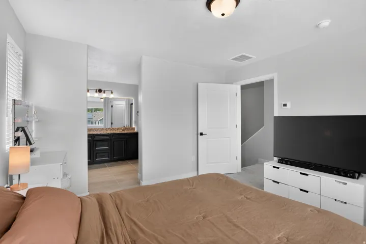 Bedroom featuring a white paneled door with black hardware, a ceiling-mounted light fixture, and a window with blinds