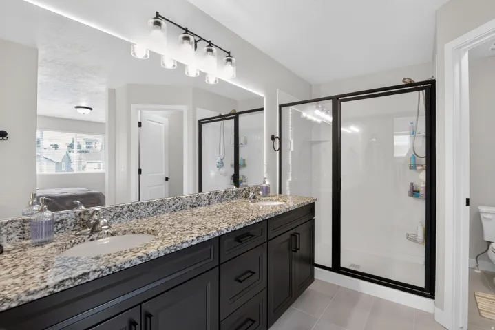 Double vanity with granite countertop and dark wood cabinetry