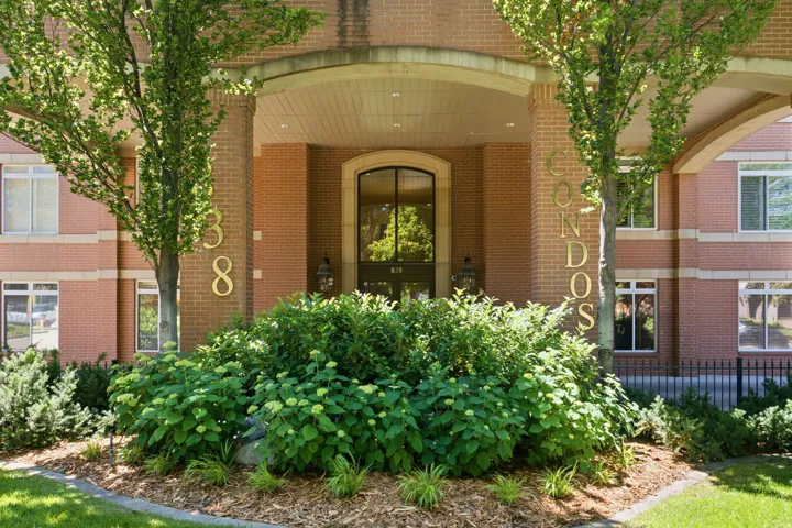 Welcome to city living! Entrance is accented with brick facade and a prominent arched entry, flanked by mature trees and lush landscaping. Controlled access entry.