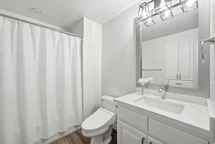 Main bathroom featuring a white vanity with updated sink, fixtures and quartz countertop.
