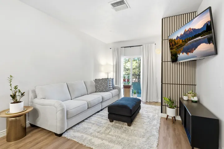 Living area featuring wood-tone luxury vinyl flooring, accent wall, and a sliding door leading to your private balcony