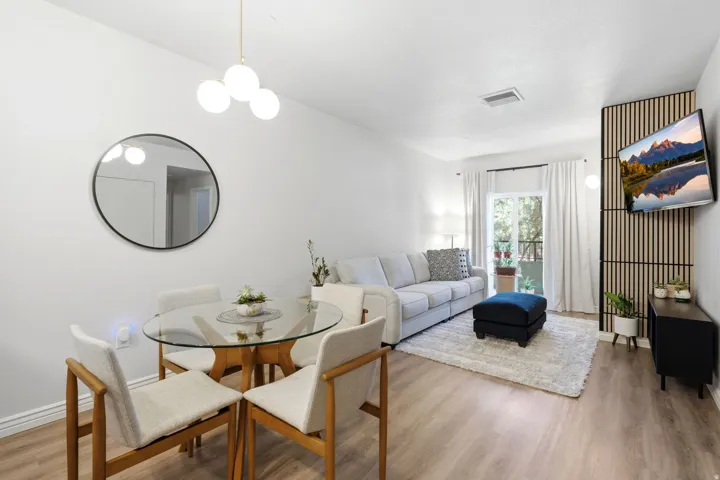 Open-concept living area featuring luxury vinyl flooring.  Room is accented with West Elm chandelier and sconce light fixtures