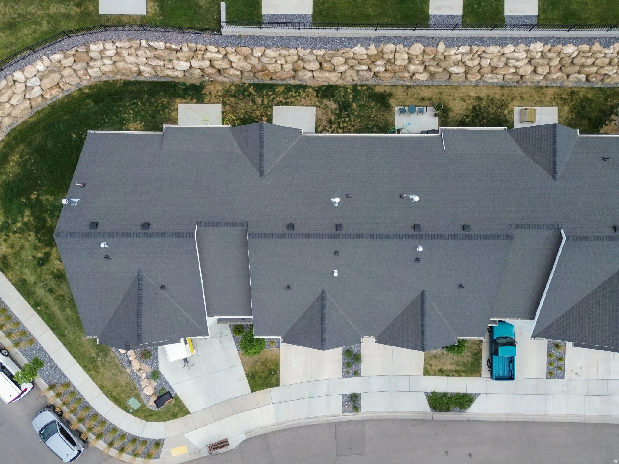 Townhome complex featuring dark grey shingle roofing and individual concrete driveways