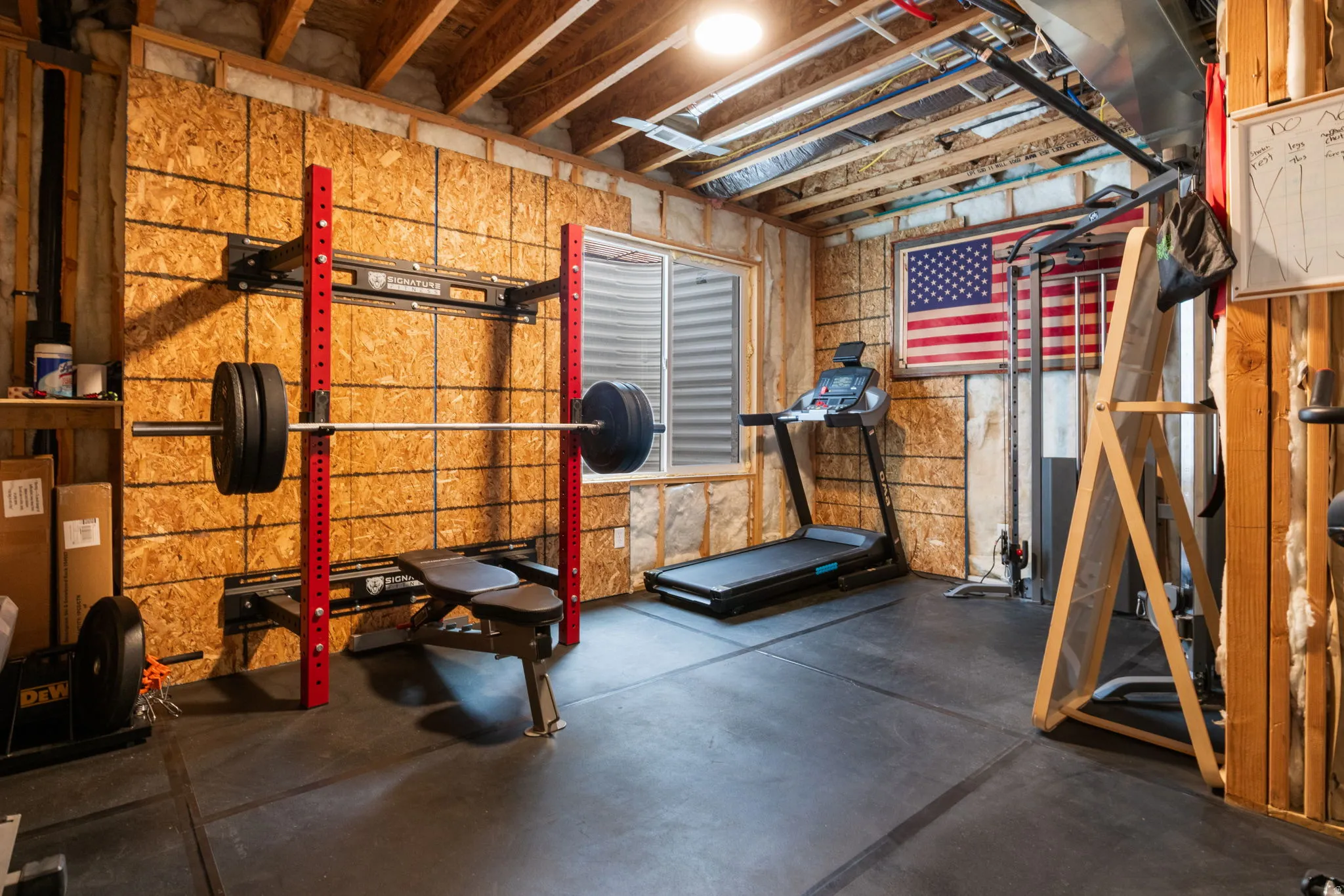Finished basement space featuring exposed ceiling joists, wood-finish wall paneling, and resilient flooring