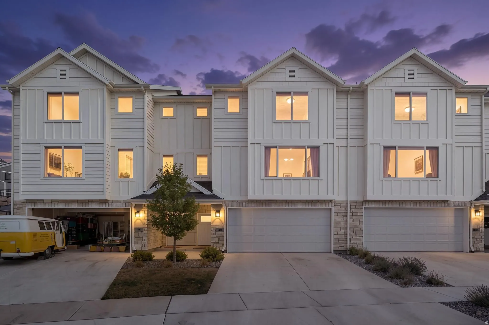 Contemporary townhome facade featuring white horizontal siding and vertical board-and-batten accents