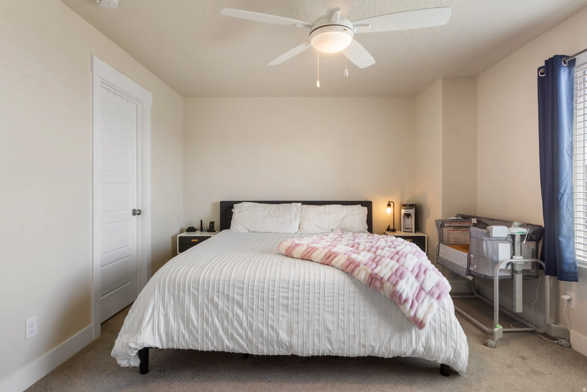 Carpeted bedroom featuring a ceiling fan with integrated lighting, a panel door, and a window with blinds