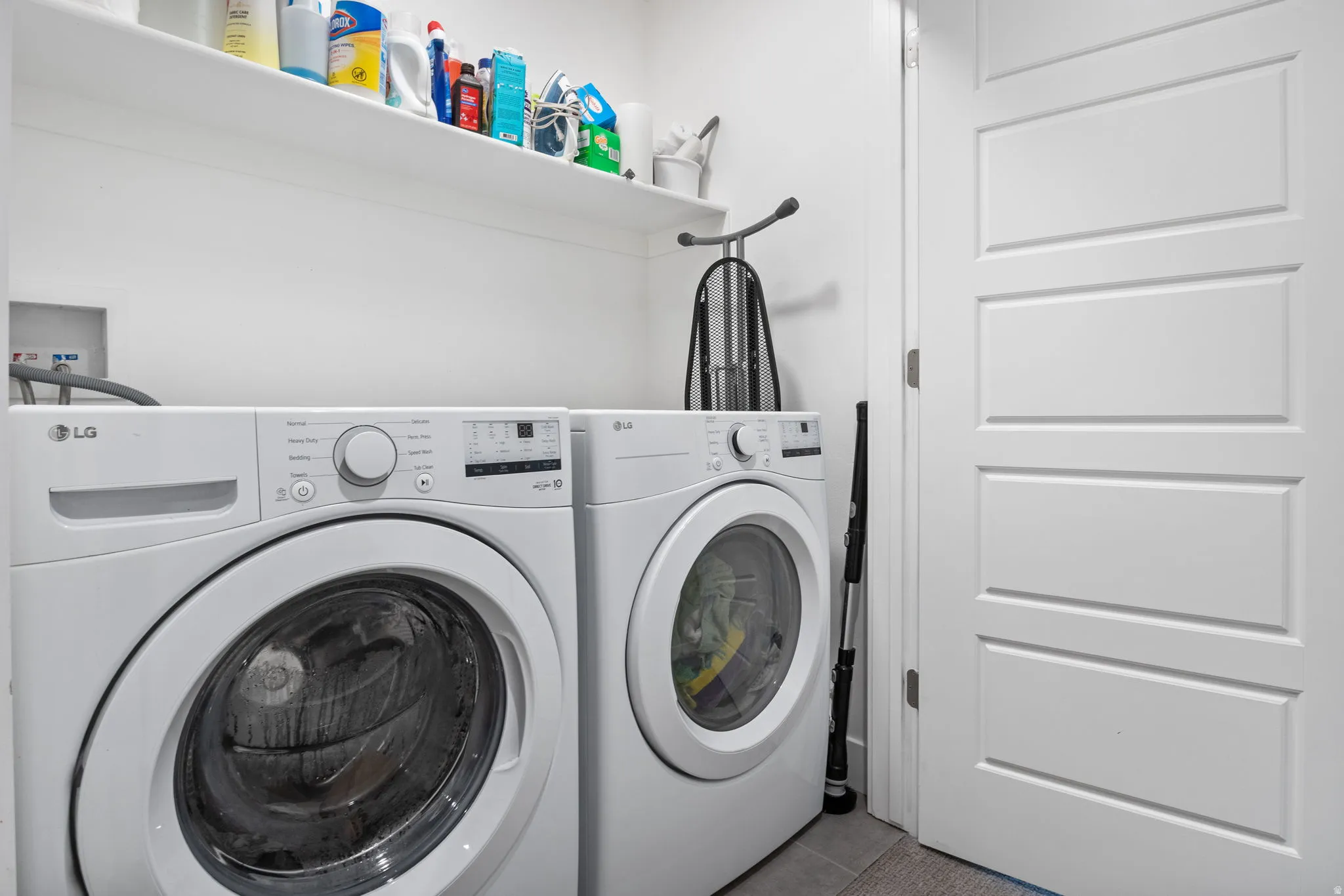 Dedicated laundry area featuring white walls, open shelving, and a paneled interior door