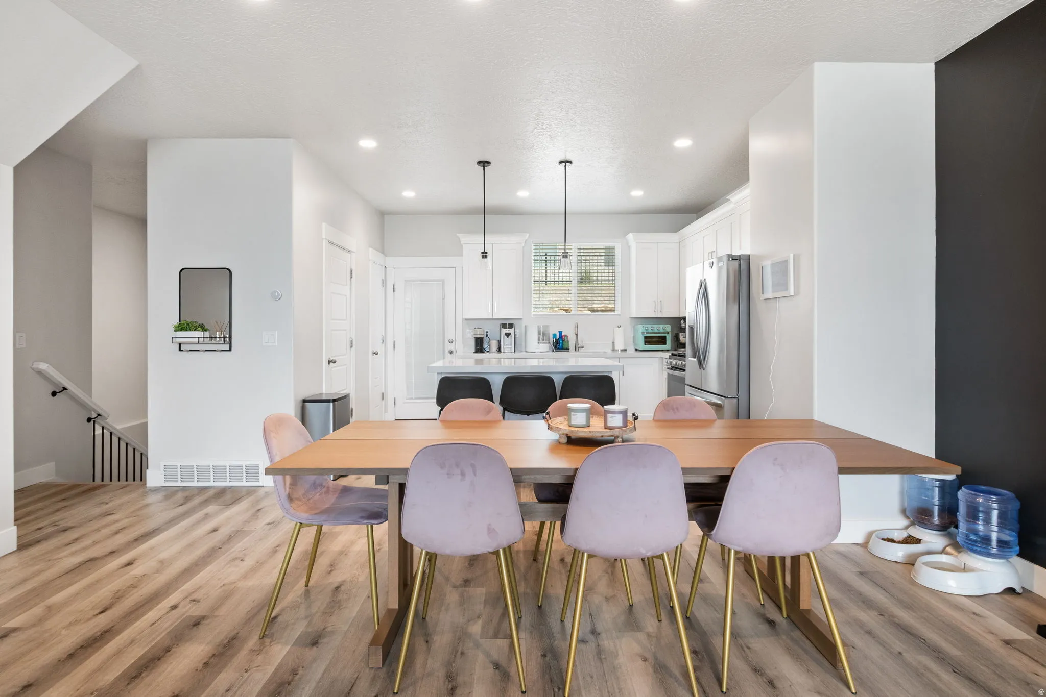 Open-concept dining and kitchen area featuring wood-finish flooring, recessed lighting, and white cabinetry