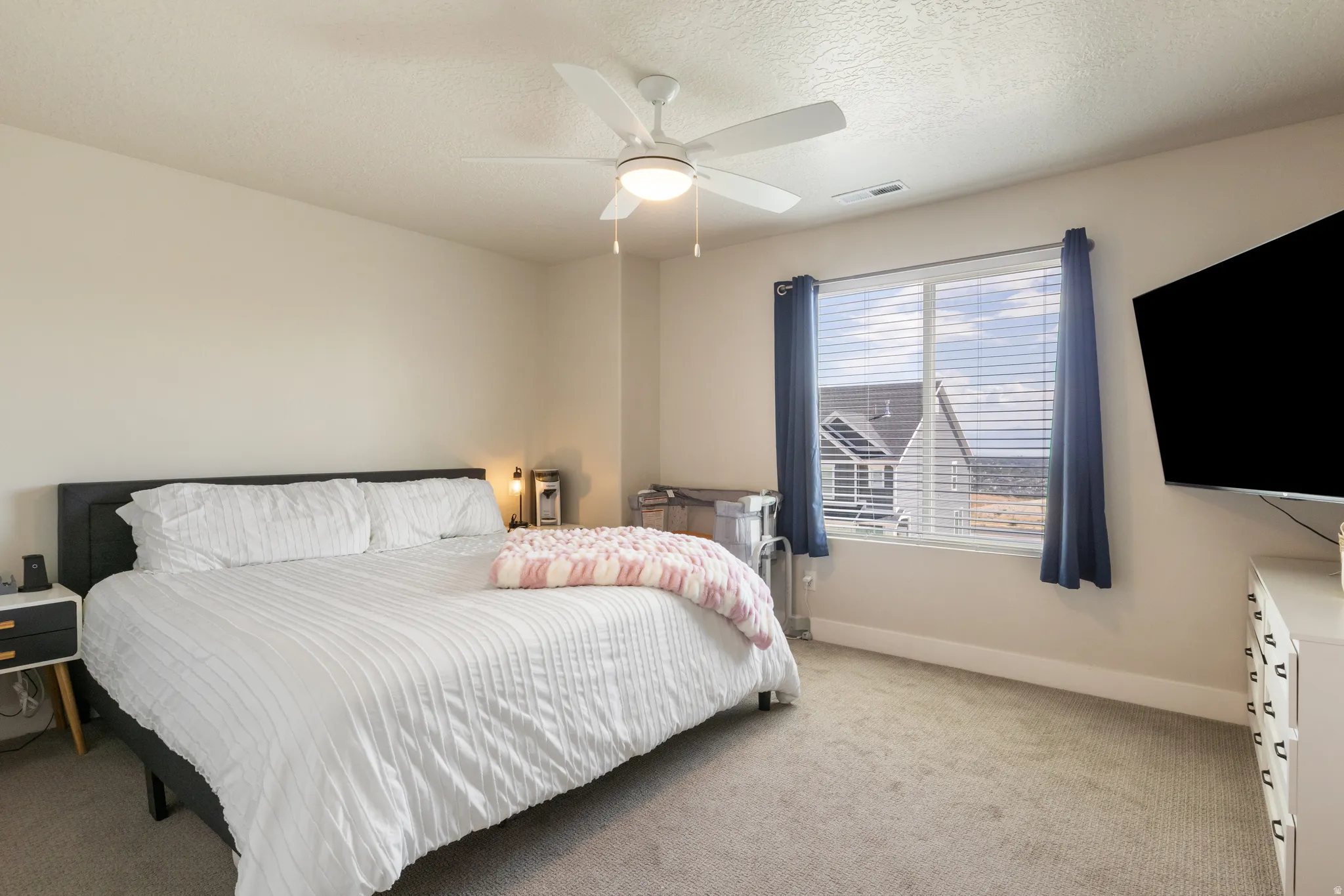 Carpeted room featuring a ceiling fan with integrated lighting, a window with horizontal blinds and drapery, and neutral wall tones