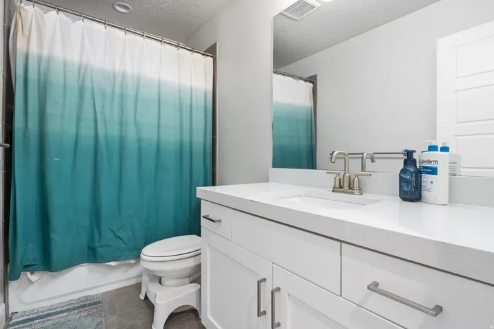 Bathroom featuring a single vanity with white cabinetry, a solid surface countertop, an undermount sink, and brushed nickel fixtures