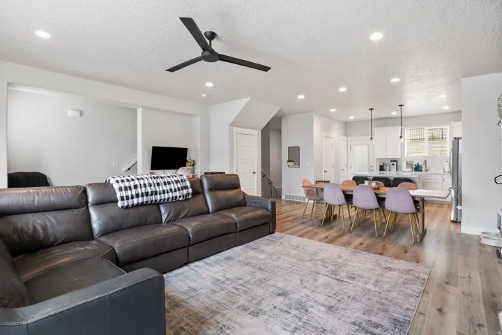 Open-concept living space featuring wood-finish flooring throughout, recessed lighting, and a modern black ceiling fan
