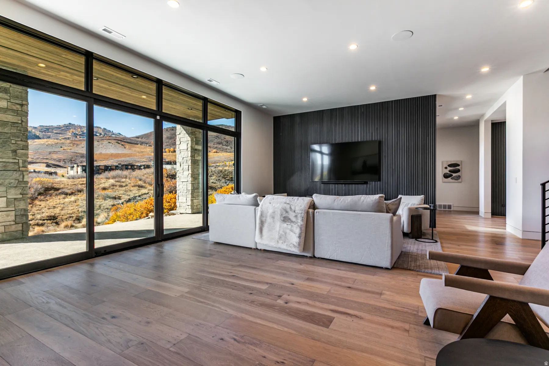 Expansive living area featuring wide plank wood-finish flooring, recessed lighting, and a textured dark accent wall