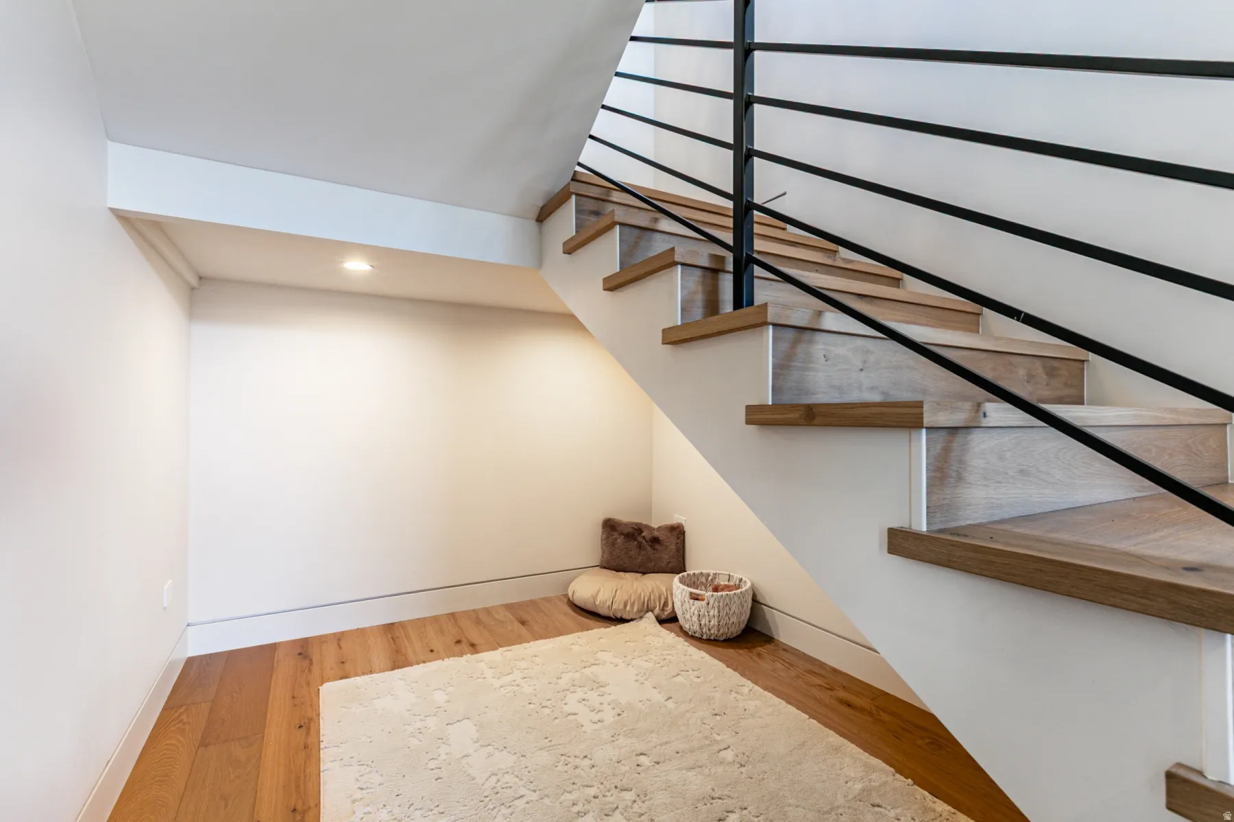 Modern staircase featuring wood-finish treads and risers, with a sleek black horizontal metal railing