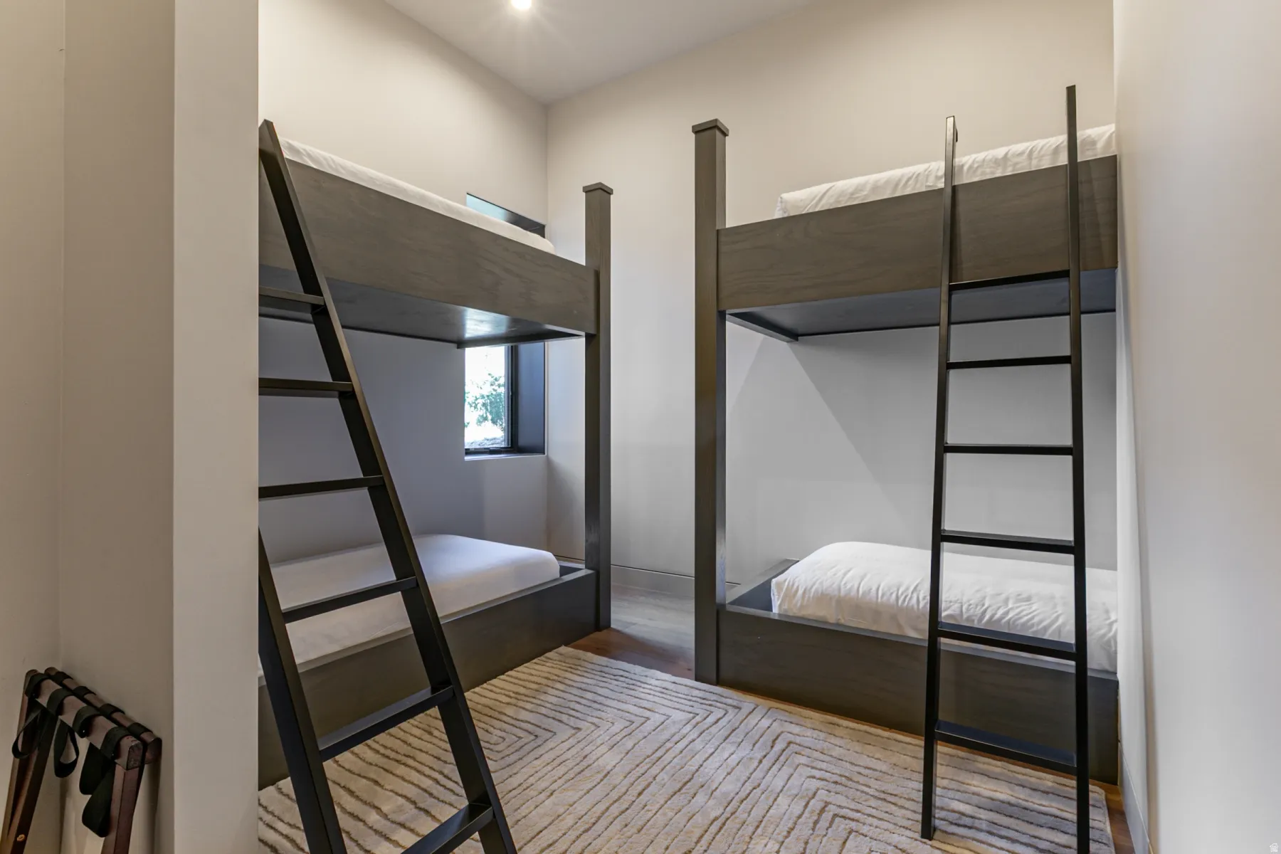 Room featuring two built-in bunk beds with dark wood-finish frames and black metal ladders