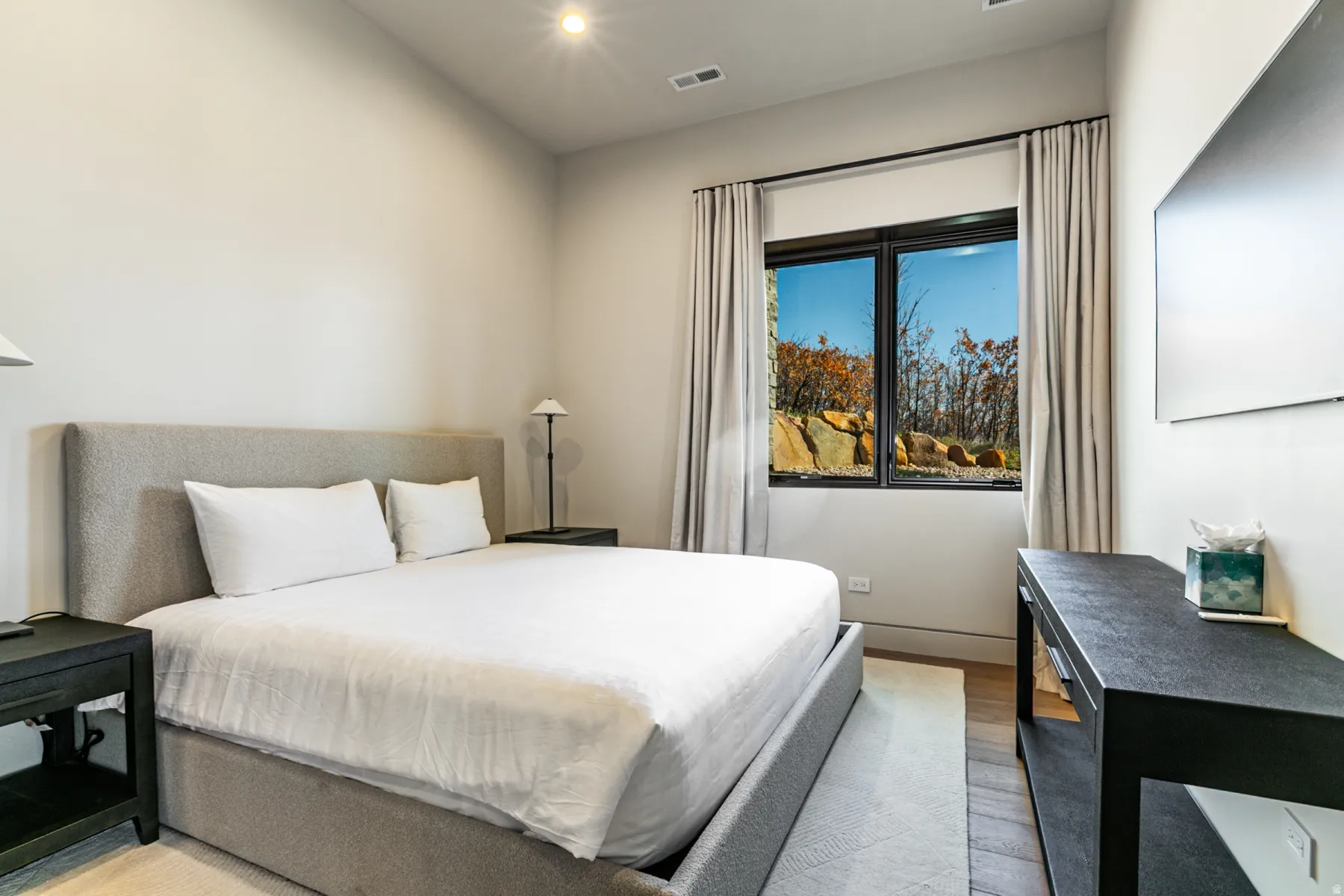 Bedroom with a large window featuring natural rock and tree scenery
