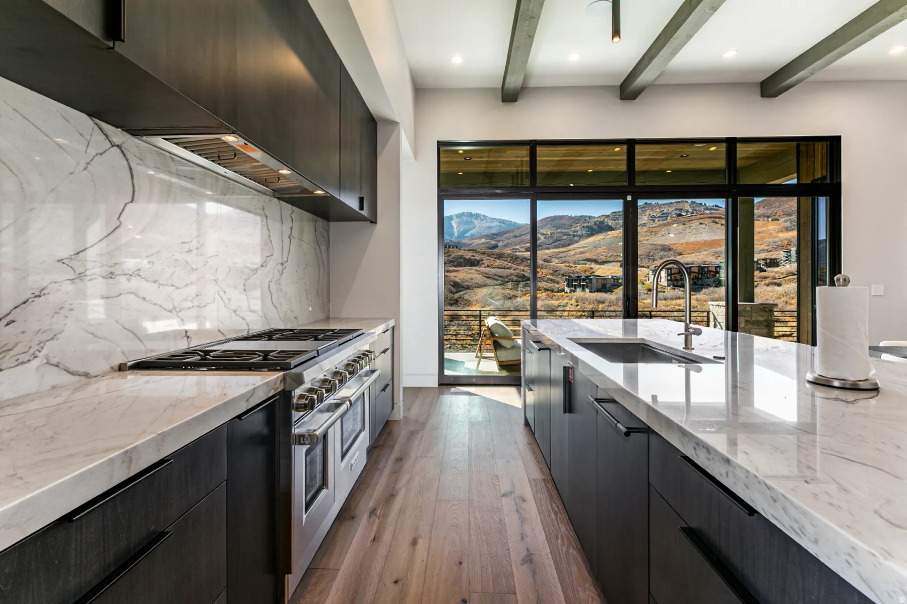 Gourmet kitchen featuring a large range with a professional-grade hood, white countertops with prominent veining, and dark wood-finish cabinetry