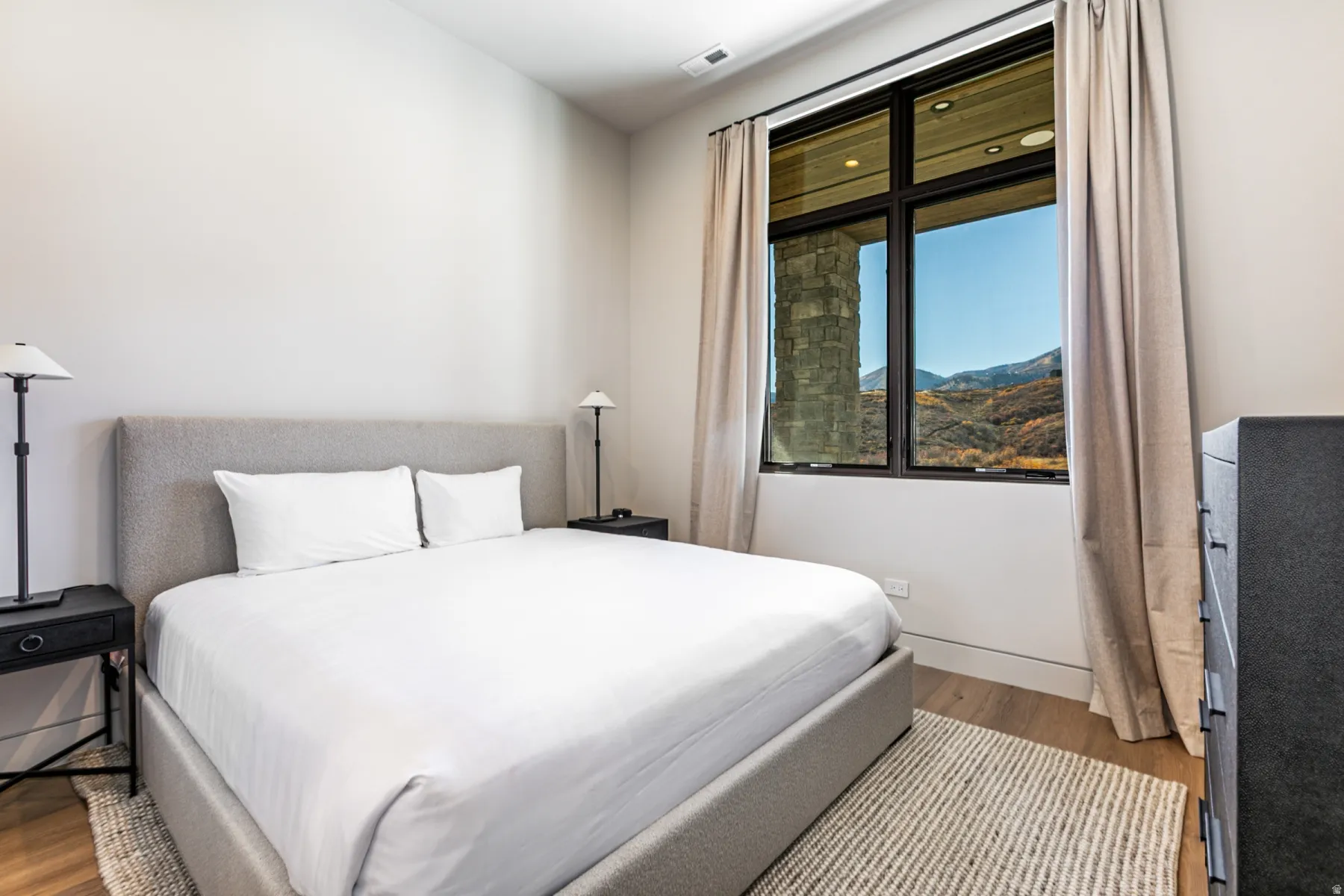 Bedroom featuring a large multi-pane window, light wood-finish flooring, and neutral wall tones