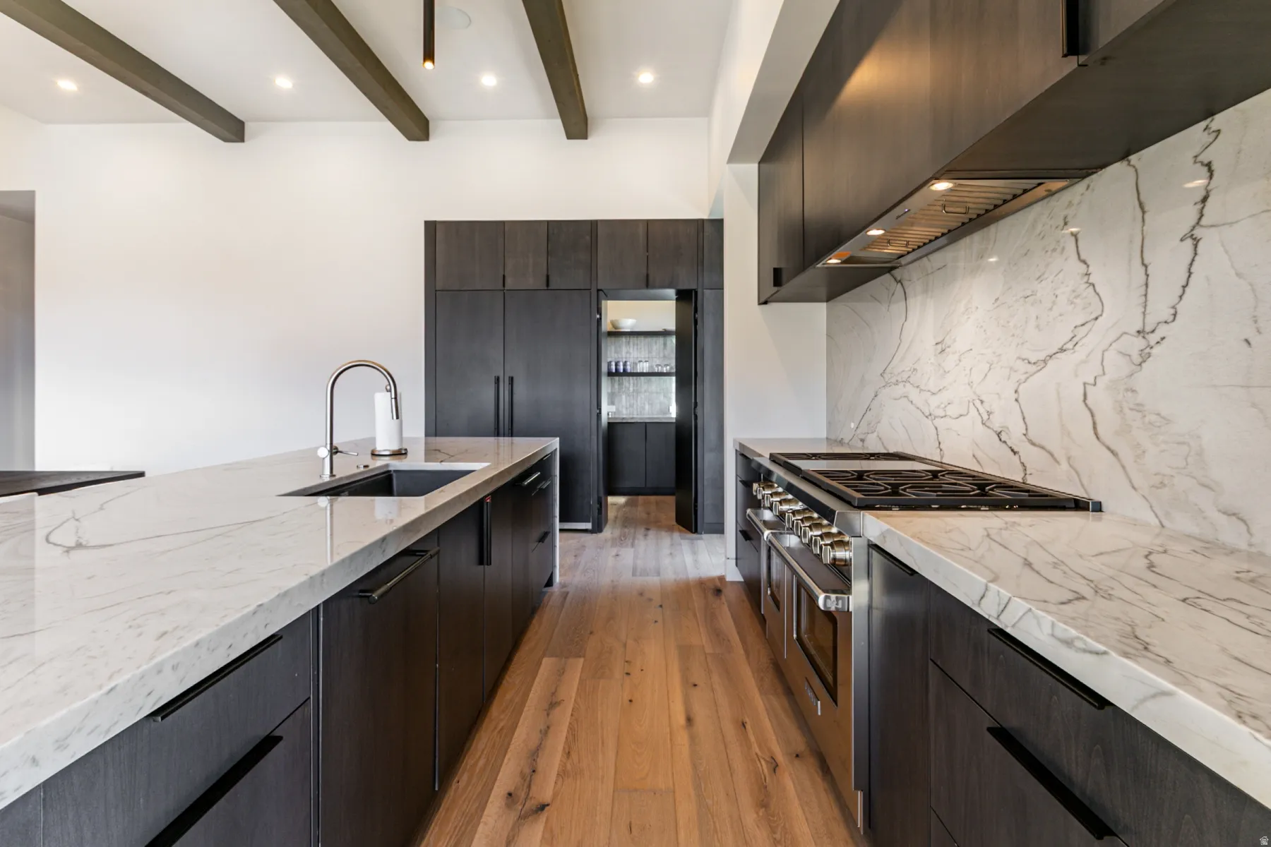 Gourmet kitchen with wood-finish flooring, exposed ceiling beams, and recessed lighting