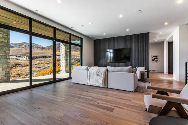 Expansive living area featuring wide plank wood-finish flooring, recessed lighting, and a textured dark accent wall