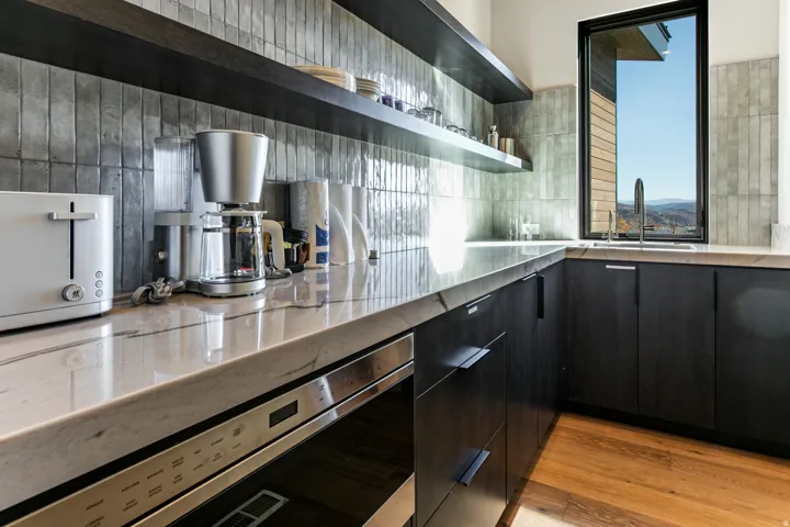 Contemporary kitchen featuring dark wood-finish cabinetry, light stone countertops, and a tiled backsplash