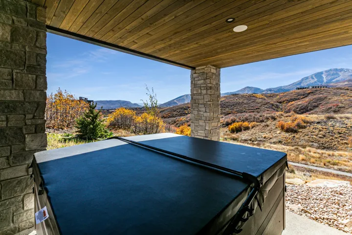 Covered outdoor patio featuring stone columns and a wood-finish ceiling, with a built-in spa