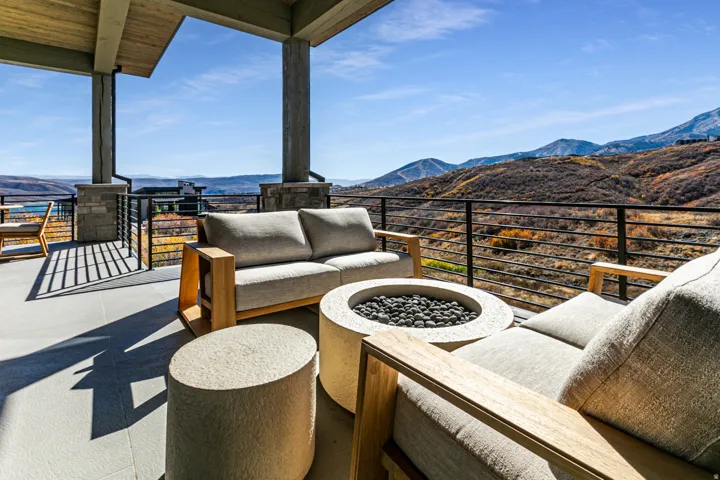 Covered patio featuring a concrete tile surface, stone-clad pillars, and a black horizontal cable railing system