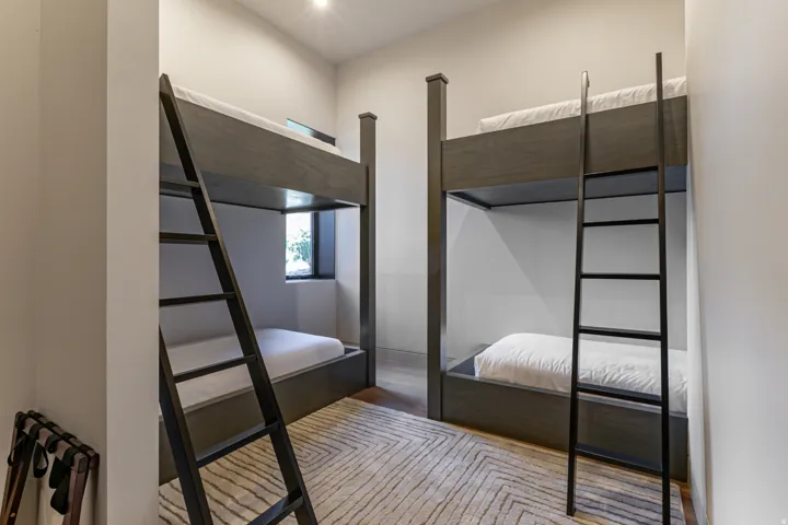 Room featuring two built-in bunk beds with dark wood-finish frames and black metal ladders
