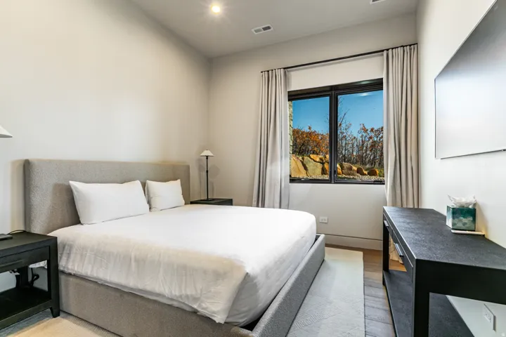 Bedroom with a large window featuring natural rock and tree scenery