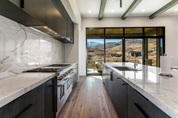 Gourmet kitchen featuring a large range with a professional-grade hood, white countertops with prominent veining, and dark wood-finish cabinetry
