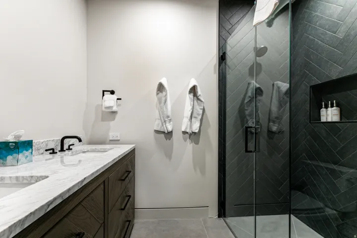 Bathroom featuring a dual vanity with a light-toned countertop, wood-finish cabinetry, and matte black fixtures