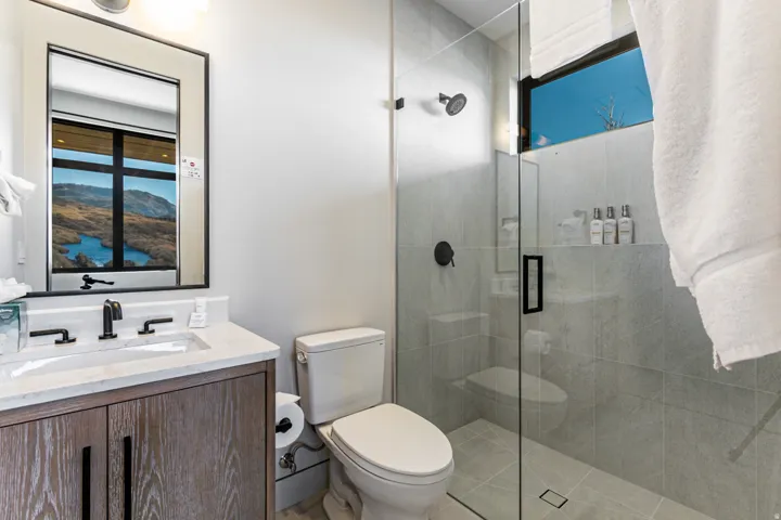 Contemporary bathroom featuring a floating wood-finish vanity with a rectangular sink, a stone countertop, and matte black fixtures