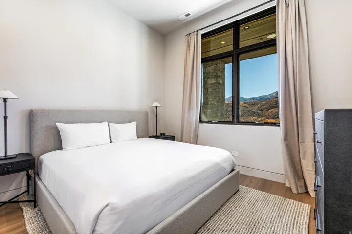 Bedroom featuring a large multi-pane window, light wood-finish flooring, and neutral wall tones