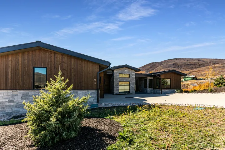 Contemporary exterior featuring wood-finish siding, stone accents, and a dark-pitched roofline