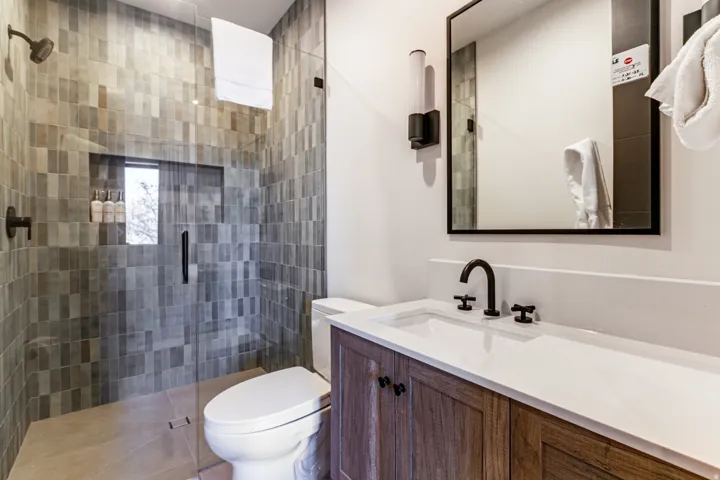 Bathroom featuring a glass-enclosed shower with gray tiled walls, a built-in shower niche, and a dark bronze shower fixture