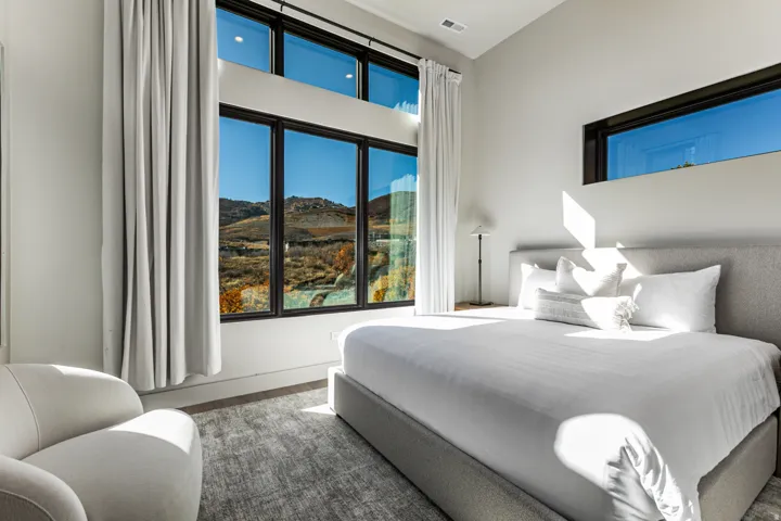 Expansive floor-to-ceiling windows with black framing, a high ceiling, and light-toned walls