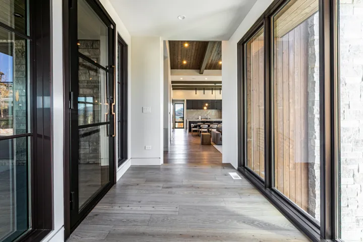 Entryway featuring wood-finish flooring, full-height windows with dark frames, and a stone accent wall