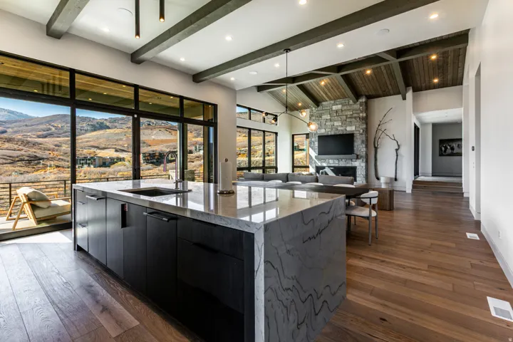 Gourmet kitchen island with an undermount sink, waterfall countertop, and dark wood-finish cabinetry