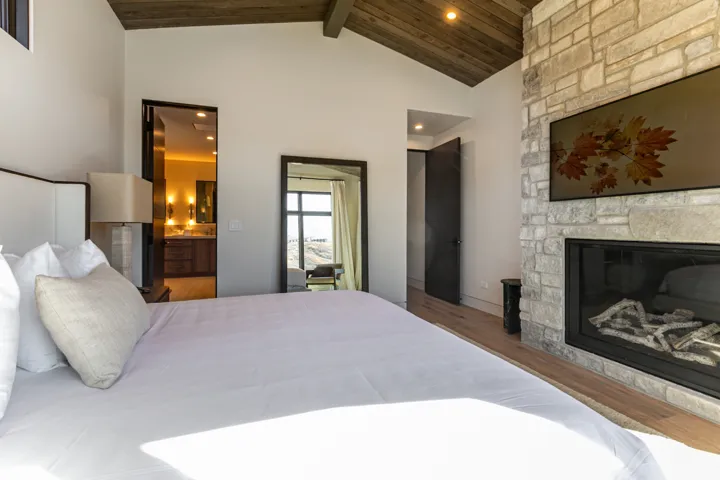 Spacious room featuring a stone-clad fireplace with a built-in television, wood-finish flooring, and a vaulted wood-paneled ceiling